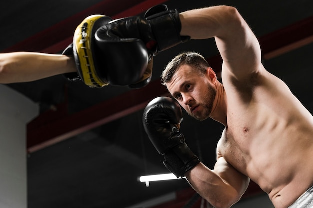 Hombre de ángulo bajo recibiendo ayuda para entrenar duro