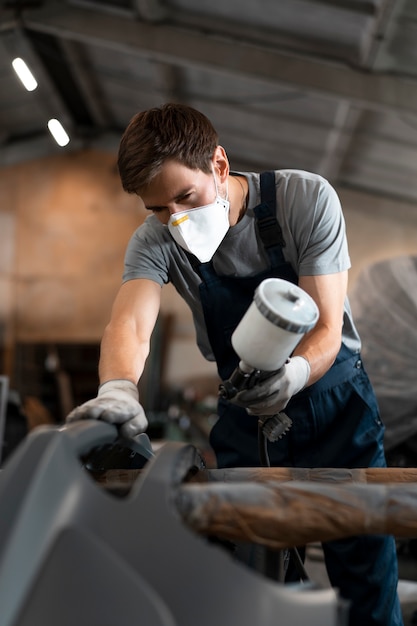 Foto gratuita hombre de ángulo bajo rociando pintura en polvo