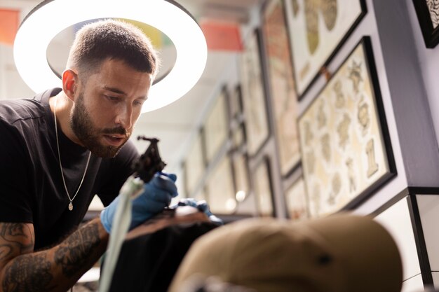 Hombre de ángulo bajo tatuando con guantes