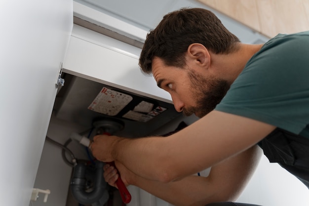 Foto gratuita hombre de ángulo bajo trabajando como fontanero