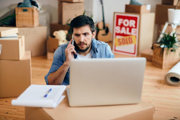 Hombre angustiado haciendo una llamada telefónica después de mudarse a un nuevo hogar