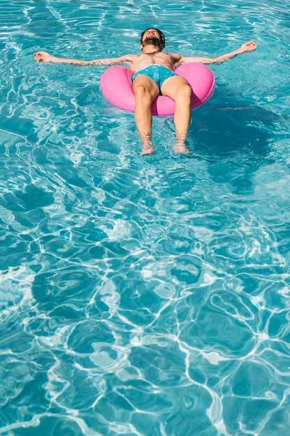 Hombre en anillo flotador en piscina