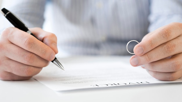 Foto gratuita hombre con anillo de matrimonio y contrato de divorcio