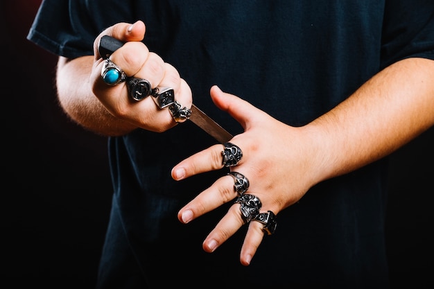 Hombre en anillos posando con daga