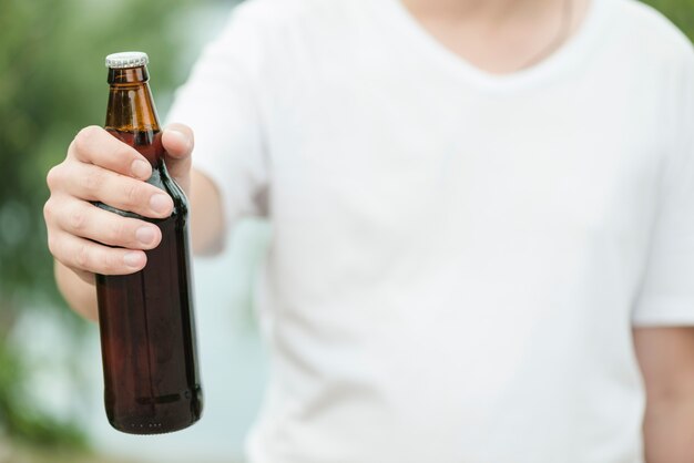Hombre anónimo que muestra la botella de cerveza