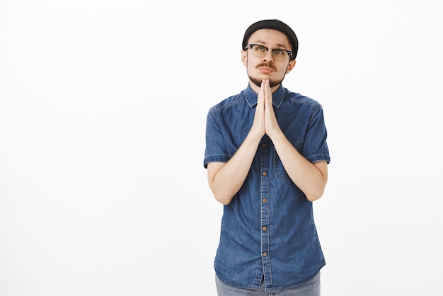 Hombre ansioso por ganar en la competencia haciendo una cara divertida frunciendo los labios y mirando al cielo tomados de la mano en oración cerca del pecho pidiendo ayuda a Dios y hacer realidad el deseo