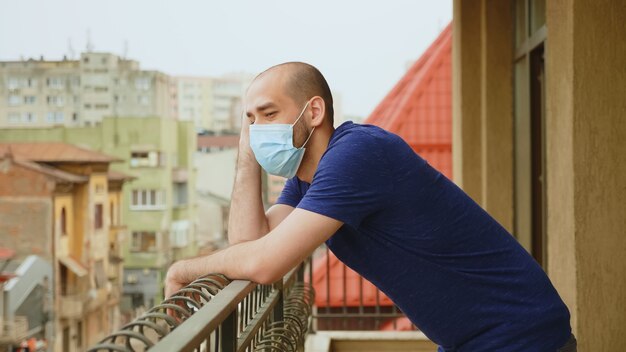 Hombre ansioso con máscara en la terraza durante la pandemia de coronavirus.