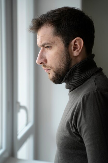 Hombre ansioso mirando por la vista lateral de la ventana