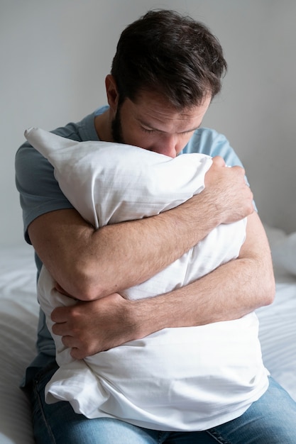 Hombre ansioso de tiro medio abrazando la almohada