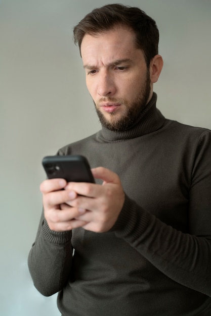 Hombre ansioso de tiro medio con teléfono inteligente