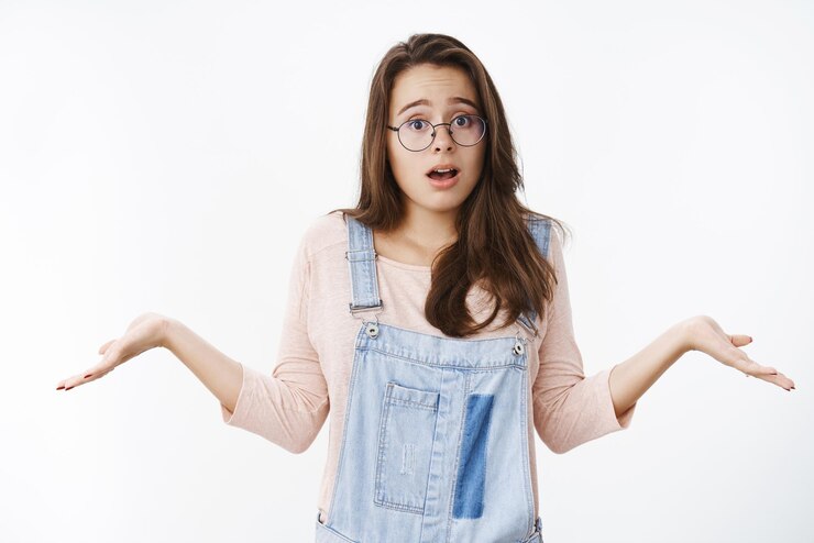Foto gratuito hombre de anteojos encogiéndose de hombros con las manos extendidas hacia los lados y la boca abierta de pie interrogado y astutamente sobre gris, inconsciente.