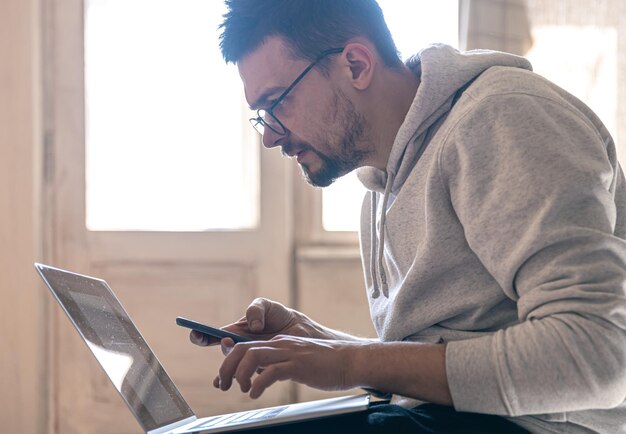 Un hombre con anteojos está trabajando en una computadora portátil.