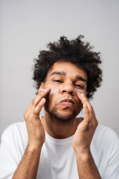 Hombre aplicando crema facial tiro medio