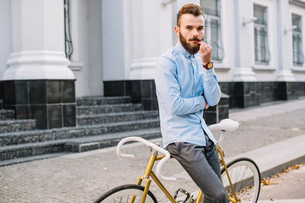 Hombre apoyado en bicicleta y tocar el bigote