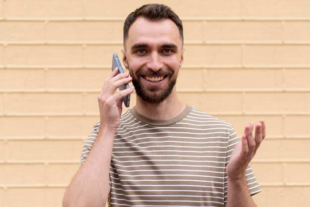 Foto gratuita hombre apoyado en una pared y hablando por teléfono