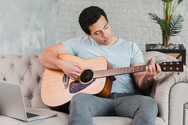 Hombre aprendiendo en línea a tocar la guitarra