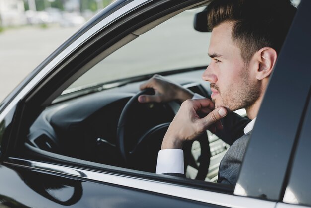 Hombre apuesto joven inteligente en el coche