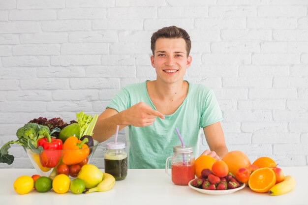 Hombre apuntando el dedo hacia las frutas frescas sobre la mesa