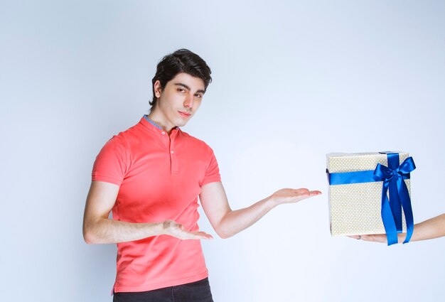 Hombre apuntando a su caja de regalo blanca con cinta azul