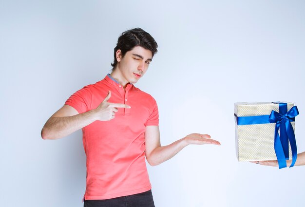 Hombre apuntando a su caja de regalo blanca con cinta azul