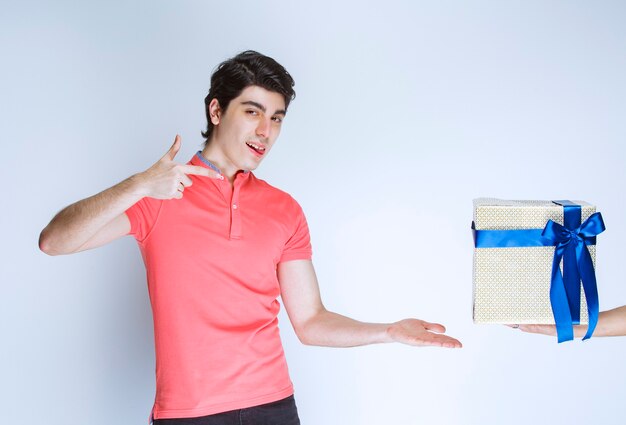 Hombre apuntando a su caja de regalo blanca con cinta azul