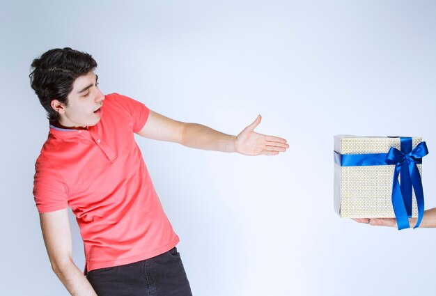 Hombre apuntando a su caja de regalo blanca con cinta azul