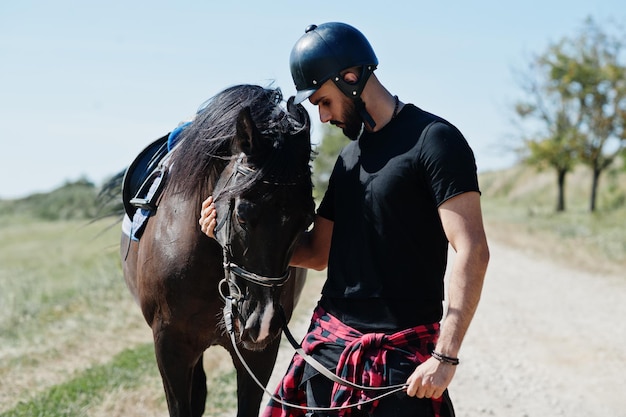 Hombre árabe de barba alta con casco negro con caballo árabe