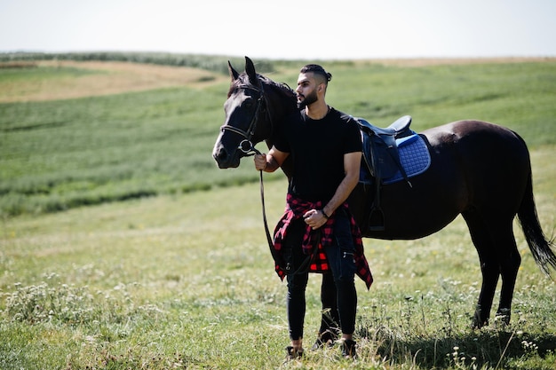 Hombre árabe de barba alta vestido de negro con caballo árabe