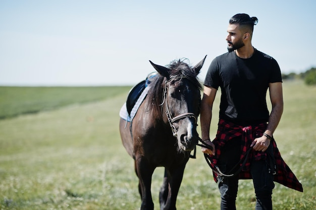 Hombre árabe de barba alta vestido de negro con caballo árabe