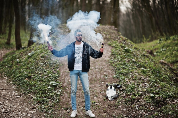 Foto gratuita hombre árabe de estilo callejero con anteojos sostiene una bengala con una bomba de granada de humo roja y azul