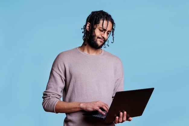 Hombre árabe pensativo que analiza el desarrollo de software mientras trabaja en una computadora portátil. Codificador joven con expresión facial pensativa que resuelve un problema mientras programa la aplicación en una computadora portátil