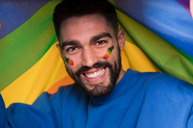 Hombre con arcoiris LGBT en la cara en el desfile gay