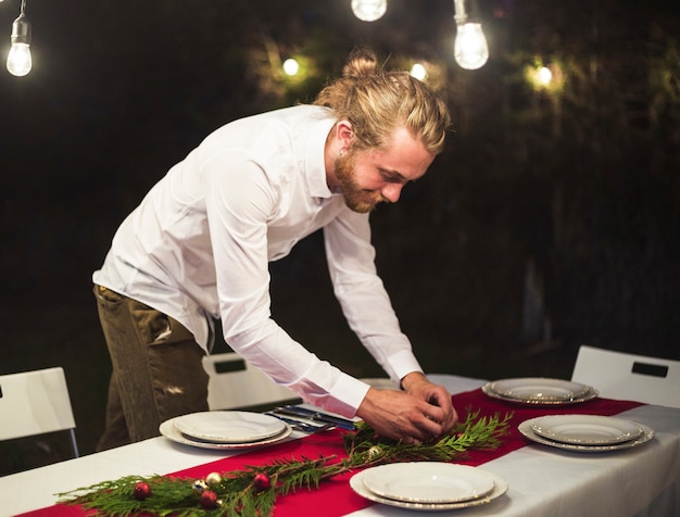 Hombre arreglando decoraciones en mesa de navidad