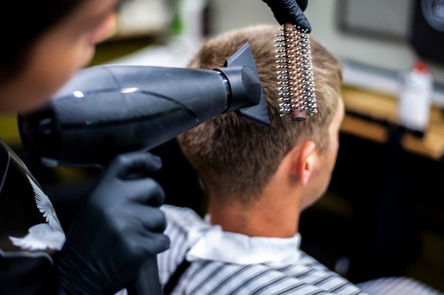 Hombre arreglando su cabello con peine y secador de pelo