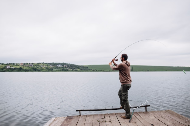 Hombre arrojando líneas de pesca en el lago