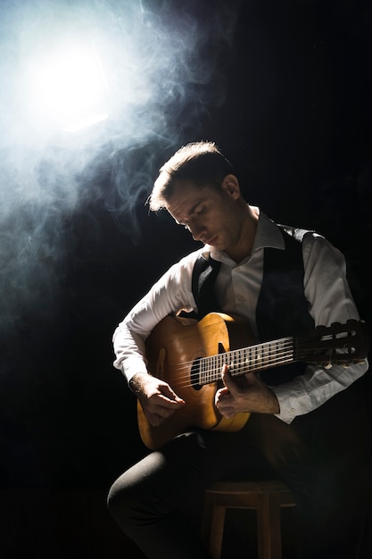Hombre artista en el escenario tocando la guitarra clásica