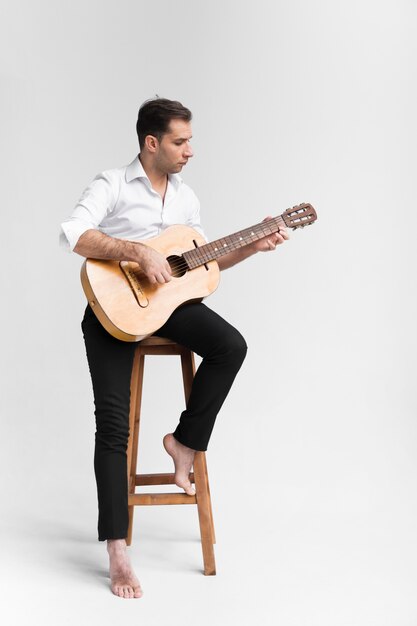 Hombre artista en estudio tocando la guitarra clásica