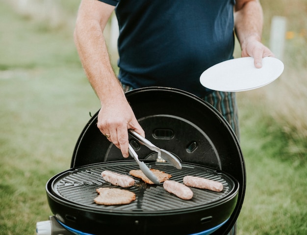 Foto gratuita hombre asar salchichas de carne al aire libre