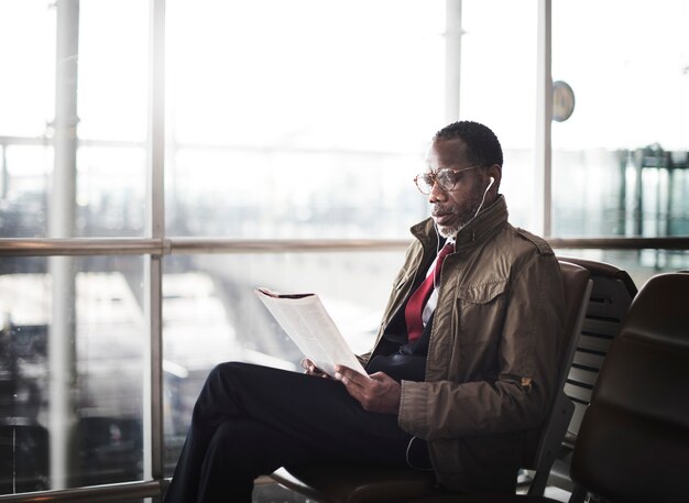 Hombre de ascendencia africana sentado leyendo la revista con auriculares