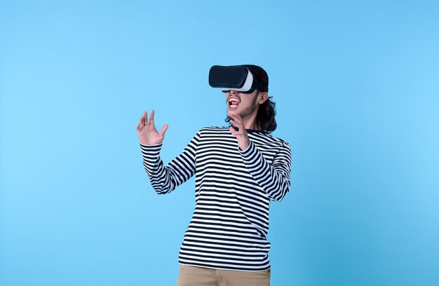 Hombre asiático emocionado con gafas de realidad virtual viendo películas en azul.