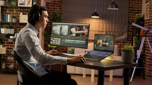 Hombre asiático escuchando música y editando videos en software, usando una computadora para trabajar en la producción de películas. Crear contenido de videógrafo con efectos visuales y degradado de color. .