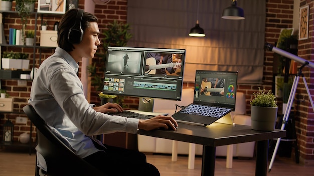 Hombre asiático escuchando música y editando videos en software, usando una computadora para trabajar en la producción de películas. Crear contenido de videógrafo con efectos visuales y degradado de color. .
