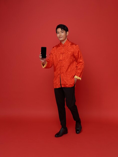 Hombre asiático feliz con vestido tradicional mostrando la pantalla en blanco del teléfono móvil