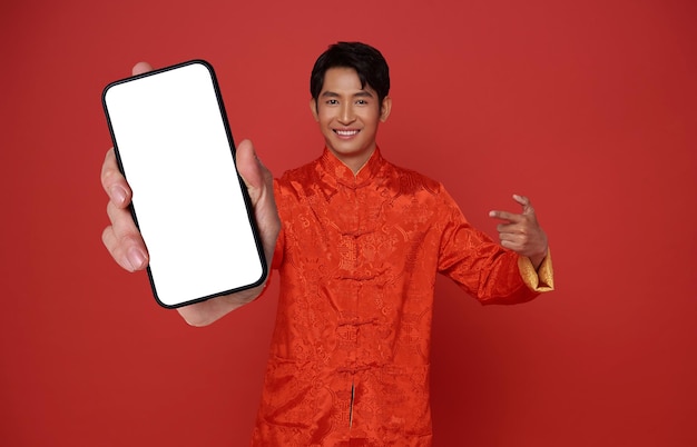 Hombre asiático feliz con vestido tradicional mostrando la pantalla en blanco del teléfono móvil