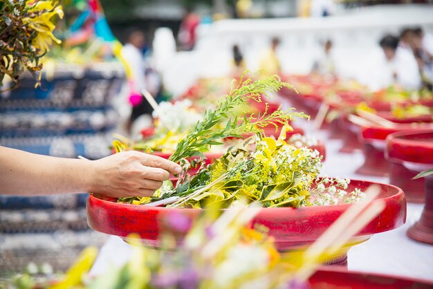 Hombre asiático con flores amarillas frescas para la participación tradicional ceremonia budista local, personas con relación religiosa