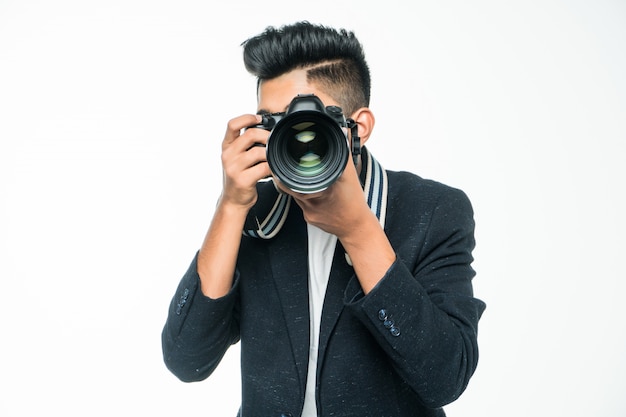 Hombre asiático joven con la cámara aislada en el fondo blanco. Concepto de fotógrafo