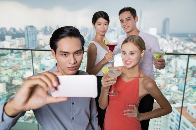 El hombre asiático joven que toma la foto con selfie Amigos