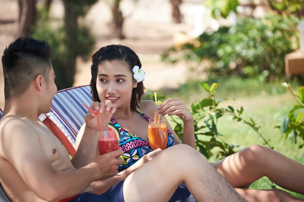 Hombre asiático y mujer bebiendo cócteles en lujoso resort tropical