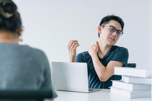 El hombre asiático que trabaja duro con el síndrome de la oficina tiene un problema con parte del cuerpo, el brazo, el hombro, la cabeza, el cuello, la espalda, el concepto de ideas de problemas saludables