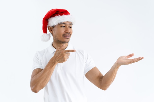 Hombre asiático sonriente que lleva el sombrero de Papá Noel y que presenta el producto